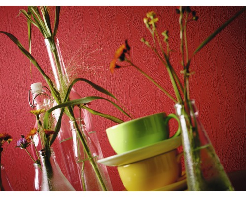 Dekorative Stillleben-Szene mit Blumen in Flaschen und gestapelten Tassen.