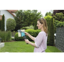 Frau hält eine Waschbürste im Garten