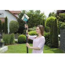 Frau benutzt eine Waschbürste mit Teleskopstiel zur Reinigung im Garten.