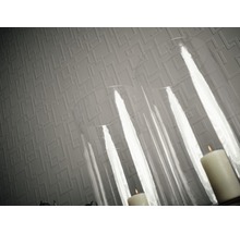 Nahaufnahme einer strukturierten Tapete mit geometrischem Muster und Kerzen in einem Glaswindlicht