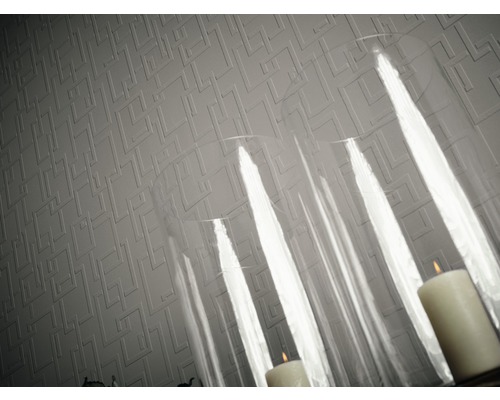 Nahaufnahme einer strukturierten Tapete mit geometrischem Muster und Kerzen in einem Glaswindlicht