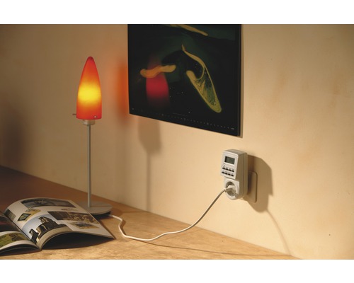 Innenraumszene mit einer Tischleuchte, einer Zeitschaltuhr und einem aufgeschlagenen Magazin