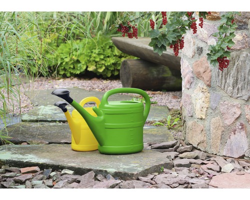 Zwei Gießkannen aus Kunststoff in einem Garten.