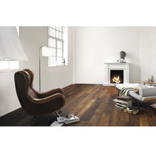 Wohnzimmer mit Kamin, Sessel und dunklem Holzboden