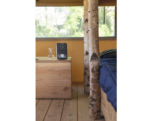 Innenraumansicht eines Zeltes mit Holzfußboden, Nachttisch, Heizgerät und Bett