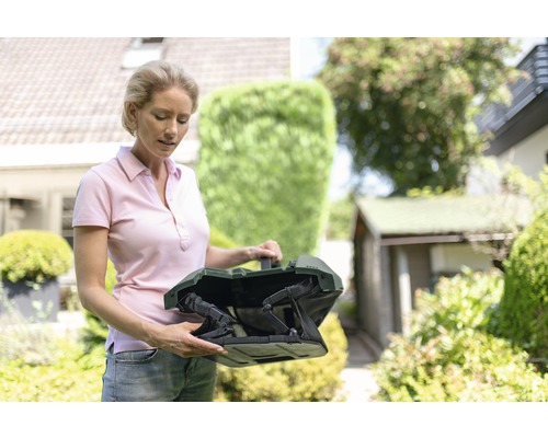 Frau hält Grasfangkorb für Rasenmäher im Garten