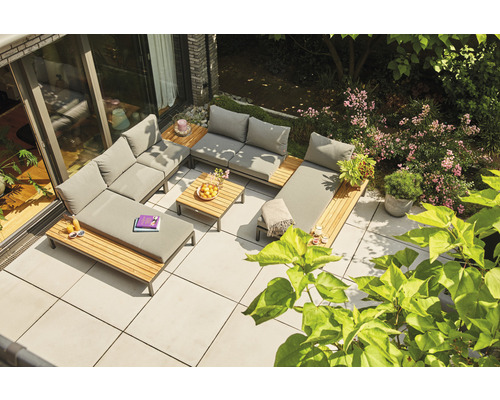 Gartenlounge-Set auf einer Terrasse mit Holzdetails und grauen Polstern, umgeben von üppigem Grün