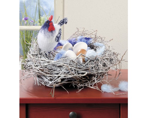 Dekoratives Osternest mit Huhn, Federn und Eiern als Tischdekoration