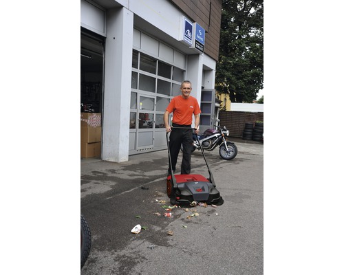 Mann kehrt Hof mit einer Kehrmaschine