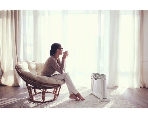 Frau sitzt in einem Sessel neben einem ROWI Heizkörper