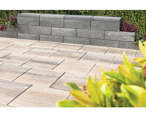 Graue Mauersteine und helle Pflastersteine im Außenbereich.