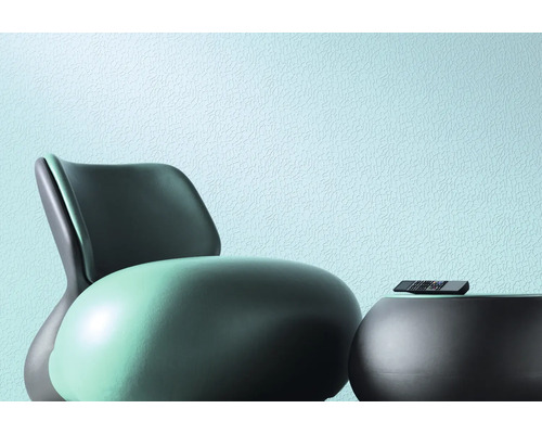 Szene mit Sessel, Tisch und Fernbedienung vor einer Wand mit Textur