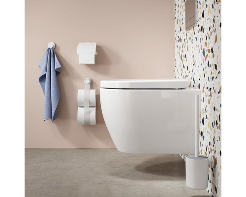 Wandhängendes WC mit WC-Bürste, Toilettenpapierhalter und Handtuchhalter im Badezimmer.