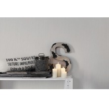 Dekorative Szene mit Kissen, Dose, Kerzen und einem Buchstaben auf einem Regal