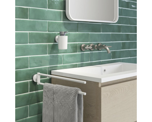 Badezimmeransicht mit Waschbecken, Armatur, Seifenspender und Handtuchhalter vor Wandfliesen