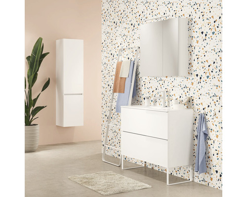 Badezimmer mit weißem Waschtischunterschrank, Spiegelschrank, Handtuchhalter und Hochschrank vor gemusterter Wand