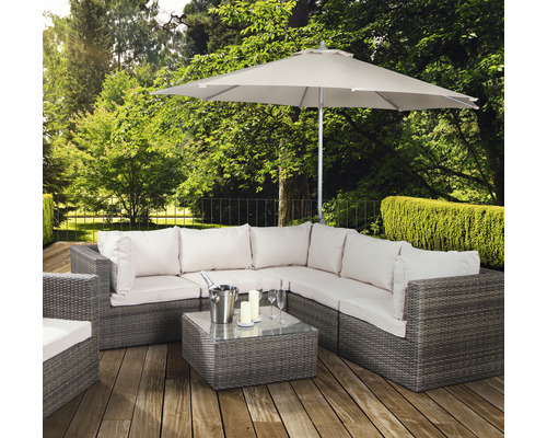 Gartenszene mit Lounge-Set aus Rattan, Tisch, Sonnenschirm, Sektkübel, Gläsern und Kerzen auf einer Holzterrasse