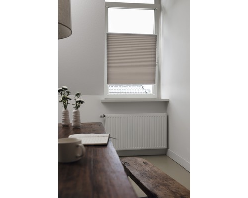 Szene mit einem Plissee am Fenster, einem Holztisch mit Dekoration und einer Sitzbank