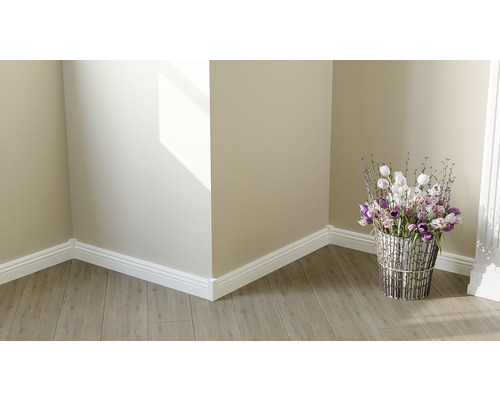 Raumecke mit Laminatboden, weißen Zierleisten und Blumenarrangement