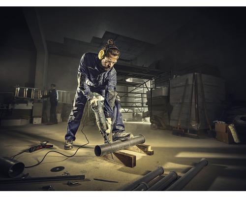 Ein Mann sägt mit einer Säbelsäge ein Rohr in einer Werkstatt