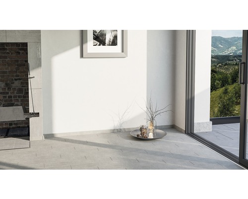 Heller Raum mit Fliesenboden, Kamin und Blick ins Grüne