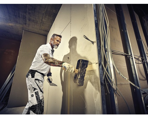 Handwerker verspachtelt eine Wand auf einer Baustelle