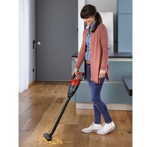 Eine Frau benutzt einen Akku-Handsauger von Einhell auf einem Holzboden in einer Küche.