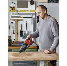 Mann saugt mit einem Einhell Akku-Handsauger Holzspäne von einer Werkbank.