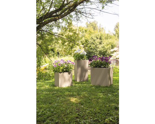 Drei bepflanzte Pflanzkübel auf einer Rasenfläche im Garten.