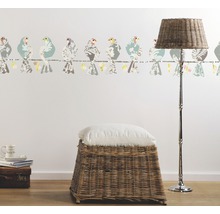 Raumansicht mit Vogelbordüre, Korbhocker, Kissen und Stehlampe.