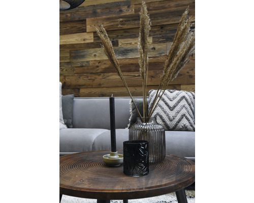 Dekoratives Wohnzimmer mit Sofa, Tisch und Accessoires wie Kerzen, Windlicht und einer Vase mit Ziergras