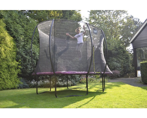 Mädchen springt auf einem Gartentrampolin mit Sicherheitsnetz