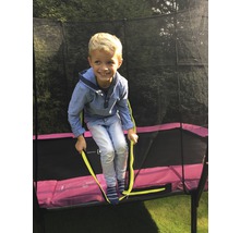 Ein Kind klettert auf ein Gartentrampolin mit Sicherheitsnetz.