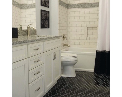 Badezimmer mit weißen Fliesen, Waschtisch und schwarzem Mosaikboden.