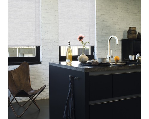 Helle Küche mit zwei Rollos an den Fenstern, schwarzer Kücheninsel und Lederstuhl