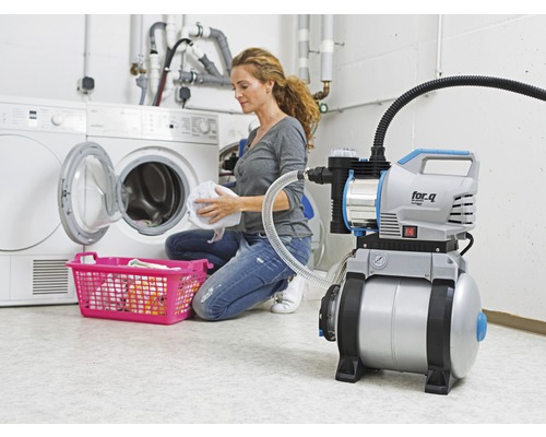 Hauswasserautomat neben Waschmaschine und Wäschekorb in einem Waschraum