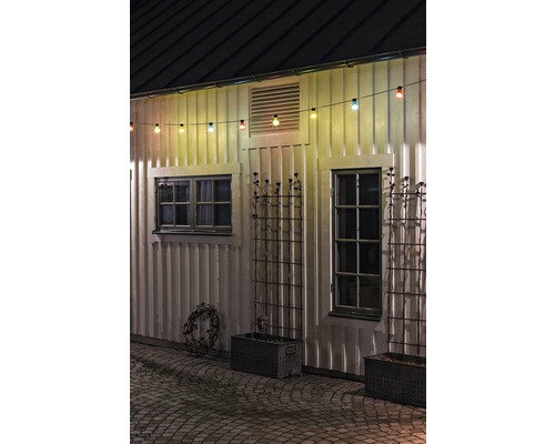 Außenansicht eines Hauses mit Lichterkette, Fenstern und Pflanzkästen.