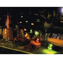 Abendliche Gartenszene mit Getränken, Snacks und dekorativer Beleuchtung.