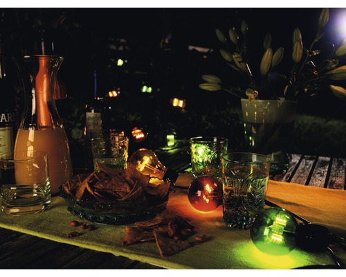 Abendliche Gartenszene mit Getränken, Snacks und dekorativer Beleuchtung.