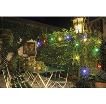 Außenbereich mit grünen Gartenmöbeln, beleuchtet mit einer Lichterkette und einer Laterne.