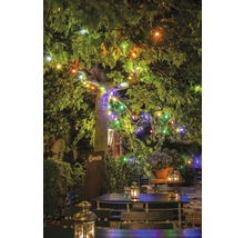 Illuminierter Garten mit Tischen, Stühlen und Laternen unter einem Baum mit Lichterketten.