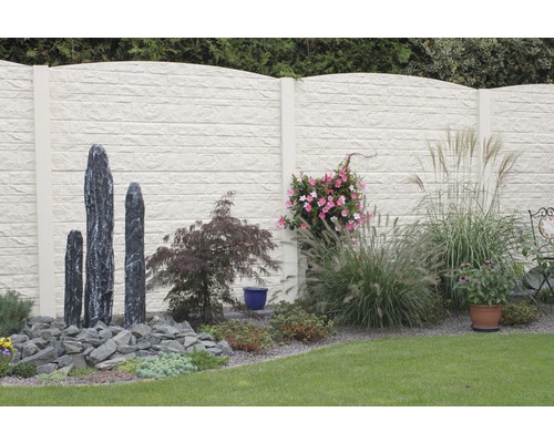 Gartenszene mit Betonzaun, Steinskulpturen und Bepflanzung