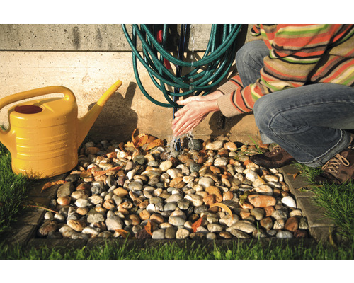 Gartenbewässerungsszene mit gelber Gießkanne, Wasserschlauch und Person, die sich die Hände wäscht