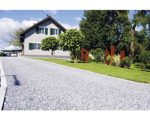 Auffahrt mit Kies vor einem Wohnhaus mit Garten