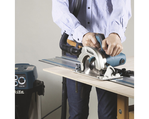 Mann schneidet Holz mit einer Makita Handkreissäge und Führungsschiene, verbunden mit einem Staubsauger