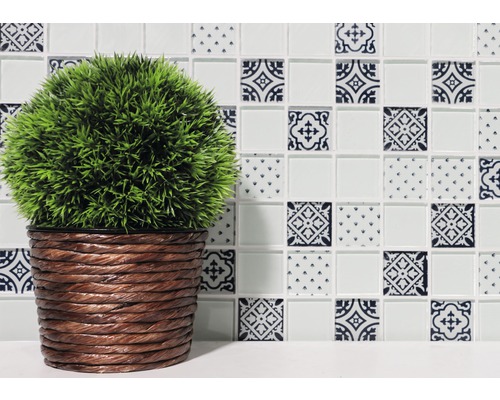 Dekorative Fliese mit Muster und Kunstpflanze im geflochtenen Topf