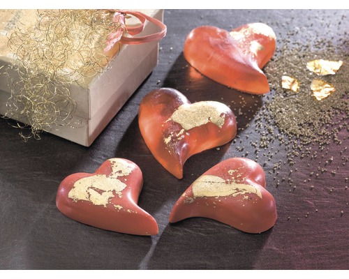 Dekorative Herzseifenstücke mit Blattgold neben einer Geschenkbox