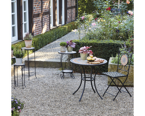 Gartenszene mit Bistrotisch, Stuhl und Pflanzenständern im Außenbereich