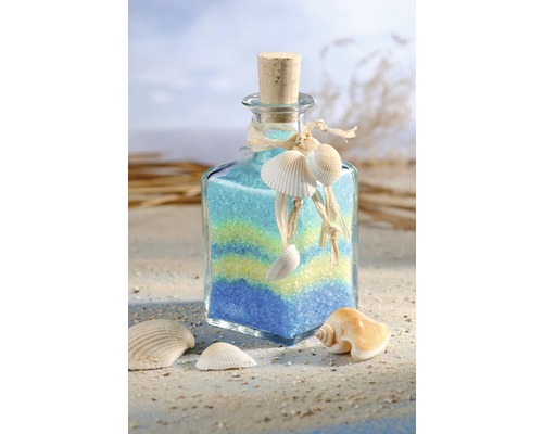 Dekorative Glasflasche gefüllt mit farbigem Sand und Muscheln