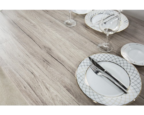 Esstisch mit Geschirr und Besteck auf einer Tischplatte in Holzoptik